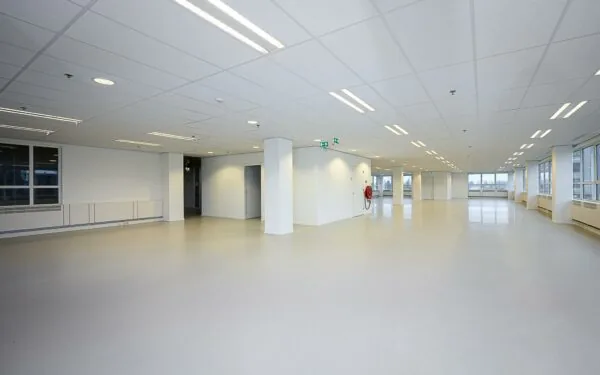 Leeg kantoorpand in Rivium Quadrant met witte muren, systeemplafond en grote ramen.